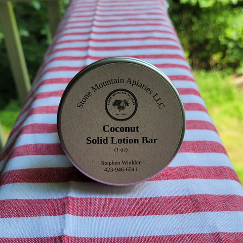 Coconut solid lotion bar from Stone Mountain Apiaries LLC on a red and white striped fabric background.