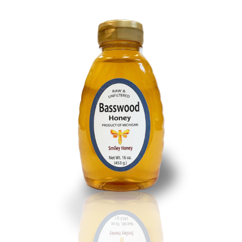 Bottle of Basswood Honey with a gold cap on a white background