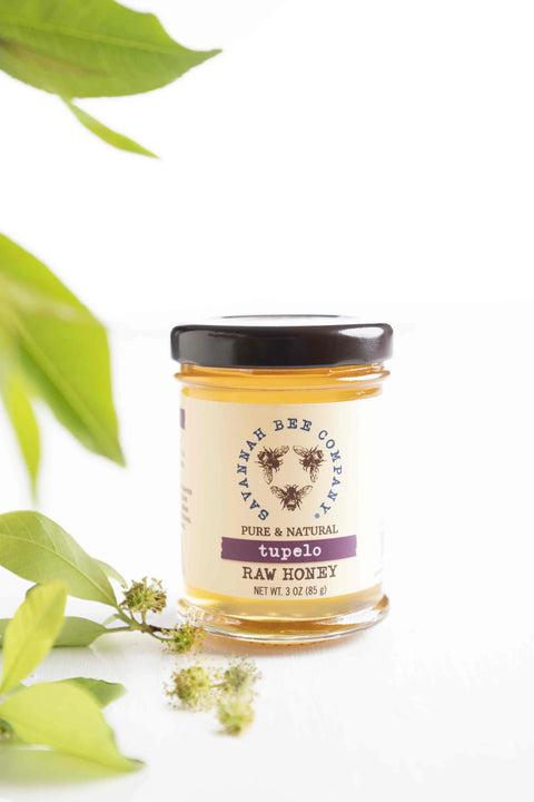 A jar of Tupelo Honey with a label indicating it is raw and unfiltered, produced by Smiley Honey, LLC, with a net weight of 2 oz (56 g).