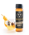Bottle of bourbon barrel-aged honey with a honey dipper on a white background