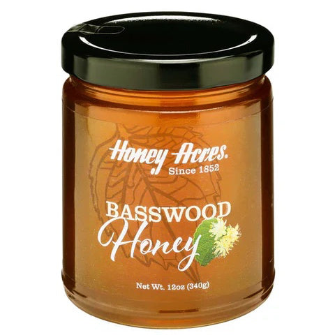 A jar of Basswood Honey with a label that includes the brand name and the type of honey. The jar is filled with golden-colored honey.