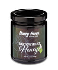 A 12 oz. jar of Buckwheat Honey with a label that includes the brand name and the type of honey. The jar is sealed with a black lid.