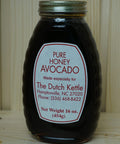 Jar of pure honey avocado spread with a label on a wooden surface