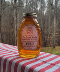 Jar of pure honey sage on a red and white striped tablecloth with a forest background
