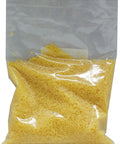 A clear plastic bag filled with yellow beeswax pellets.