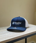 Navy and white cap with 'Foxadise Farms' logo on a wooden surface.