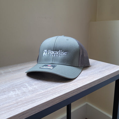Gray cap with 'Foxadise Farms' logo on a wooden surface