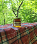 Jar of buckthorn honey on a plaid blanket with a forest background