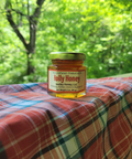 Jar of Holly Honey on a plaid surface with a green, leafy background