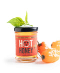 Jar of hot honey with a red label and black lid on a white background