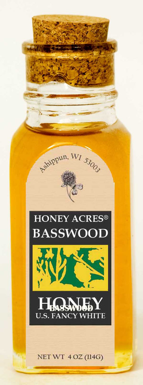 Bottle of Honey Acres Basswood Honey with cork lid on a white background