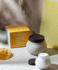 Body butter jar with a box labeled 'Savannah Bee' on a textured surface.