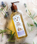 Hand soap bottle with a label on a soapy surface with herbs
