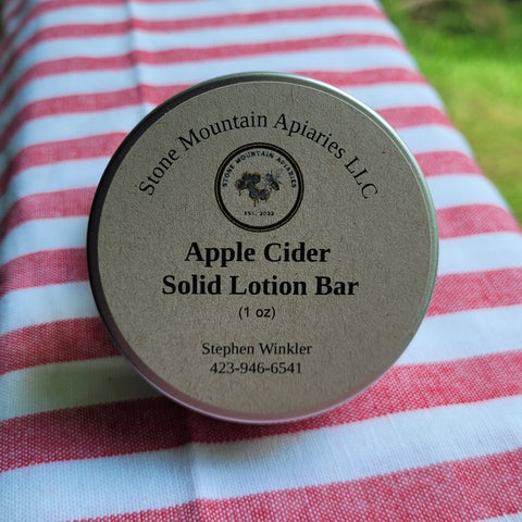 Apple cider solid lotion bar container on a striped fabric background