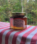Jar of cinnamon honey on a red and white striped fabric with a natural background