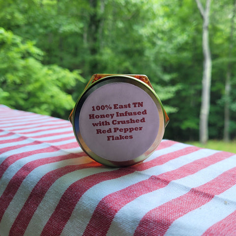 Honey container with text on a striped fabric background outdoors