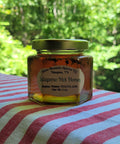 Jar of Stone Mountain Apiaries Jalapeno Hot Honey on a striped tablecloth with a blurred green background