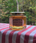 Jar of lavender honey on a red and white striped surface with a blurred natural background