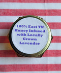 Honey jar lid with lavender text on a red and white striped fabric background