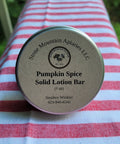 Pumpkin Spice Solid Lotion Bar on a striped fabric background