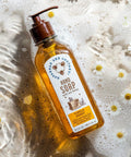 Hand soap bottle with pump on a soapy surface with daisies