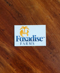 A round vinyl sticker with a blue and white design featuring a palm tree and what appears to be a fox face, placed on a wooden surface.