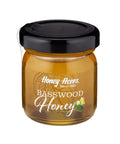 A jar of Basswood Honey with a label that includes the brand name and the type of honey. The jar is filled with golden-colored honey.