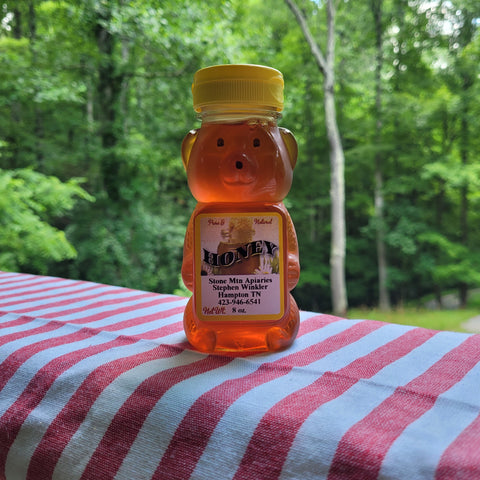 Honey bear bottle on a striped tablecloth with a forest background