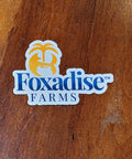 A custom-shaped magnet with the logo of Foxadise Farms printed on it, featuring a stylized fox face and the name of the farm in white and yellow colors.