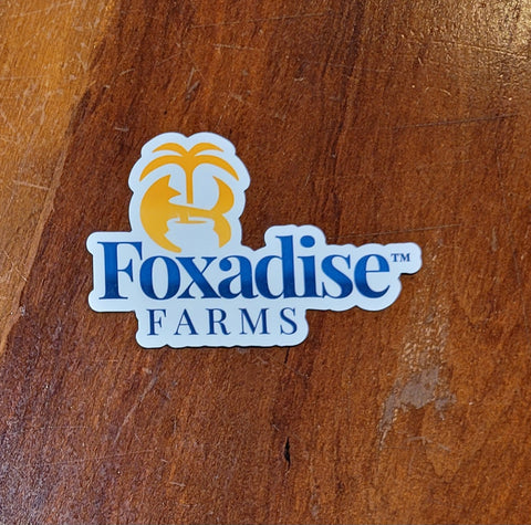 A custom-shaped magnet with the logo of Foxadise Farms printed on it, featuring a stylized fox face and the name of the farm in white and yellow colors.