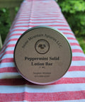 Peppermint solid lotion bar on a striped tablecloth outdoors