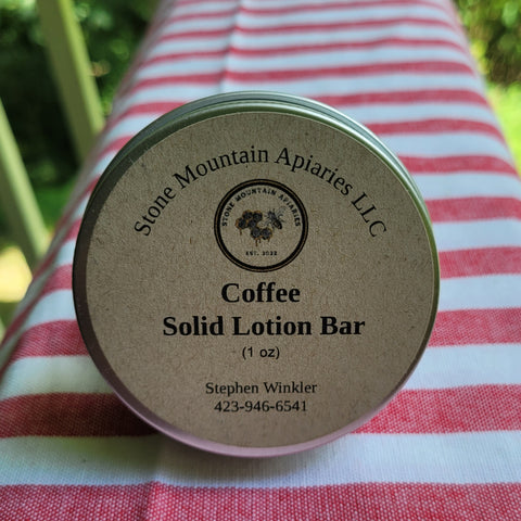 Coffee solid lotion bar container with 'Stone Mountain Apiaries LLC' branding on a striped fabric background.
