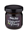 A jar of Buckwheat Honey with a label that includes the brand name and the type of honey. The jar is sealed with a black lid.