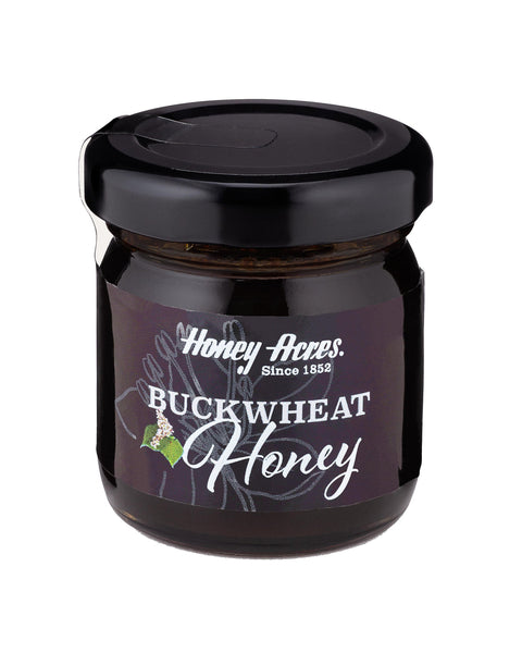 A jar of Buckwheat Honey with a label that includes the brand name and the type of honey. The jar is sealed with a black lid.