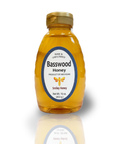 Bottle of Basswood Honey with a gold cap on a white background
