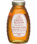 A jar of pure orange blossom honey from The Dutch Kettle, with a label indicating the product name and the weight of 16 oz.