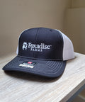 Navy and white cap with 'Foxadise Farms' logo on a wooden surface.