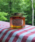 Jar of hot honey on a striped fabric with a forest background