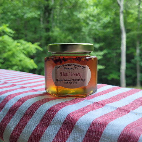Jar of hot honey on a striped fabric with a forest background