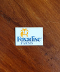 A round vinyl sticker with a blue and white design featuring a palm tree and what appears to be a fox face, placed on a wooden surface.