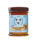 A jar of Charleston Honey with a label that includes the product name and the phrase 'Pure & Natural'. The jar is sealed with a brown lid and has a clear body showing the honey inside.