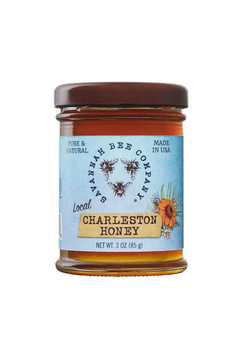 A jar of Charleston Honey with a label that includes the product name and the phrase 'Pure & Natural'. The jar is sealed with a brown lid and has a clear body showing the honey inside.