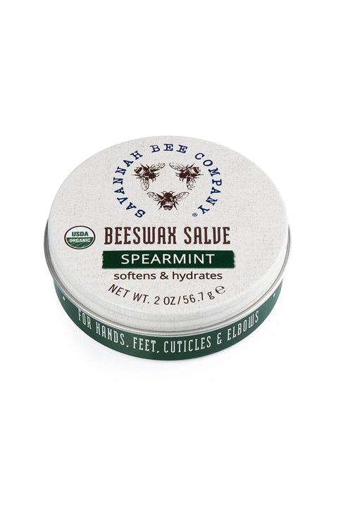 A tin container of Beeswax Salve with Spearmint. The label shows the brand name, product name, and a partial image of a bee.